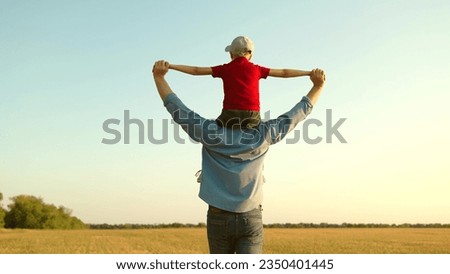 Concept of happy family, childhood dream. Father Son play together in front of sun, dream, fly. Dad, child fantasize, kid aviator sits on his fathers shoulders. Boy plays pilot airplane, hands wings