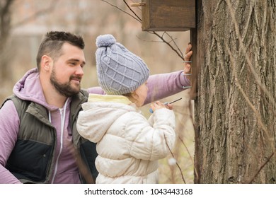 The Concept Of A Happy And Interesting Childhood. Father And Child Are Having Fun. Father And Daughter Make A Bird Feeder.