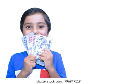 Concept Of Happy Kid Getting Pocket Money. Indoors. Child Looking Towards Camera. Excited Kid Holding Money. White Background. With Happy Expression Child With Dollars. Australian Cash Money In Hands