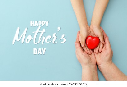 Concept Feliz Día de la Madre o Día Internacional de las Familias. Feliz día de la mujer. Corazón en manos de la hija y la madre en un fondo azul. Te amo. Cartel de venta. Tarjeta de saludo. Vista superior. Banner