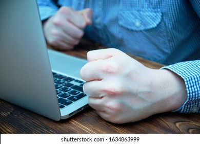 The Concept Hate And Anger On The Internet, Forums And Chat. Clenched Fists Of A Man In Front Of A Laptop. Close Up.