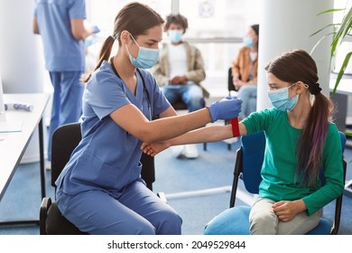 Concept of healthcare and medicine. Female laboratory assistant in face mask preparing patient to do a blood analysis. Nurse tightening the medical tourniquet on arm before taking blood sample