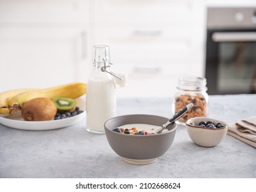 The concept of a healthy breakfast of vegetarian yogurt, granola and fresh fruit on a blue table against a white  kitchen background. Front view. - Shutterstock ID 2102668624
