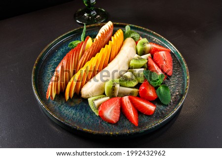 The concept of a healthy diet. Platter fruits and berries - apple, orange, banana, kiwi, strawberry, mint