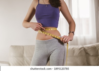 Concept of healthy eating. Young girl with perfect waist with a measuring tape in hands