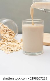 Concept Of Healthy Grain, Pour Oat Milk Into Glass And Oat Flakes Poured Out Of Glass Jar.