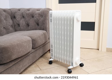 Concept of heating season, modern electric heater near sofa