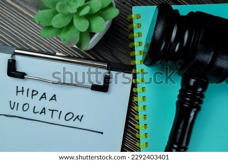 Concept of HIPAA Violation write on paperwork isolated on Wooden Table.