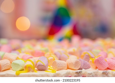 Concept Of Holiday Or Birthday. Multicolor Five Layer Cake With Colored Marshmallow On The Top And Defocused Lights As Background