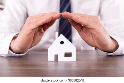 Concept of home insurance with hands over a house