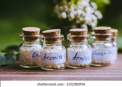Concept of homeopathy. Homeopathy pills bottle, wooden organic green leaf background