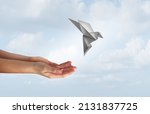 Concept of hope and freedom as human hands release a magical flying origami bird made of paper as a liberty and democracy symbol for peace and love of humanity to stop war and spirituality icon.