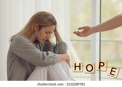 Concept Of Hope. Man Offering Hand To Upset Woman Indoors