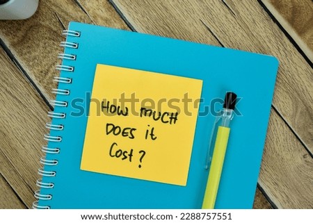 Concept of How Much Does it Cost? write on sticky notes isolated on Wooden Table.