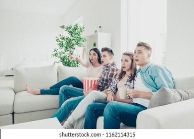 Concept of human reactions. Group hipster  of four guys sit on a sofa, in in a bright living room in casual denim wear and watching a video holding breath.  - Shutterstock ID 1162114315