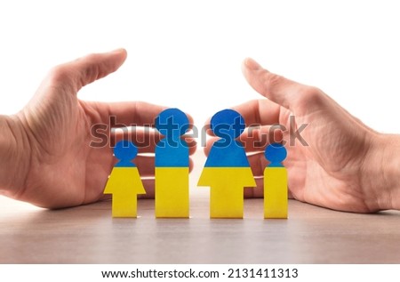 Concept of humanitarian aid for Ukrainian war refugees with cutout painted with colors of the Ukrainian flag on the table and welcoming hands behind. Stockfoto © 