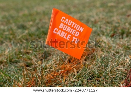 Concept image for 811 call before you dig service. Utility companies come and mark the places of buried cable tv, water, electric and gas lines using color coded spray paint and pin  flags.