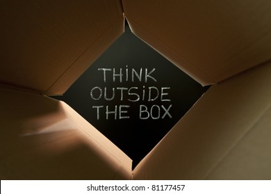 Concept image about unconventional or different thinking. Think outside the box handwritten with white chalk on blackboard.
