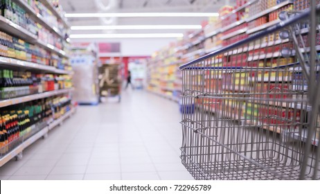 Concept image of buying. Shopping trolley in a Tesco Hypermarket with blurry background of groceries on the rack. Focused only at the trolley.