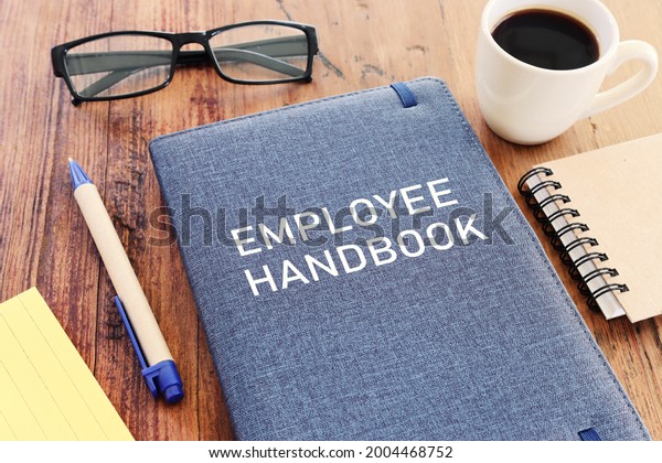Concept image of employee handbook over wooden\
office table. top view