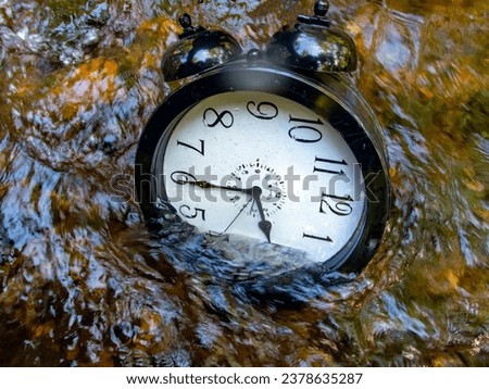 Concept image losing track of time, relativity science image, flowing time, large clock in a flowing stream with half of the clock face submerged with ripples and colors distorting the numbers