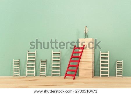 Concept image of a miniature figure progressing up a ladder to success and leadership