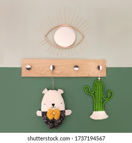 Concept Image Of A Wall As A Composition Of Home Decoration Objects Hanged Around A Wooden Wall Hanger Including An Eye Shaped Mirror, A Macrame Cactus And A Fabric Handmade Toy, Front View Interiors
