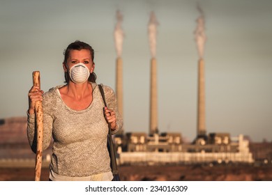 Concept Image Of A Woman Wearing A Mask And A Walking Stick Walking Away From A Coal Burning Power Plant With Dirty Smoke In The Air