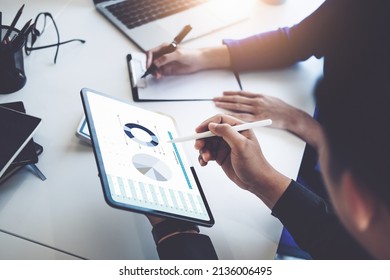 Concept of the impact of warring countries, male economists are using tablets to consult with marketing staff or accountants to adjust production and investment strategies to the current situation. - Shutterstock ID 2136006495