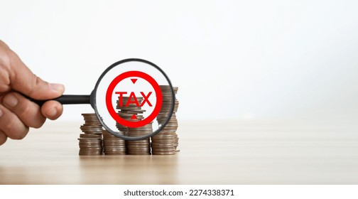 The concept of increasing taxes, subsidies. A stack of metal coins and a plastic magnifier. - Shutterstock ID 2274338371