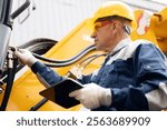 Concept industry truck maintenance. Worker with tablet inspects bulldozer at coal and sand quarry.