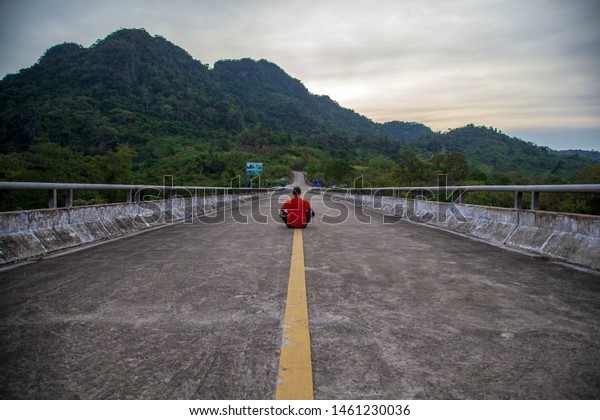 The concept of infinity and loneliness - a\
man sits on the road on the dividing\
strip