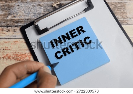 Concept of inner critic write on sticky notes isolated on Wooden Table.