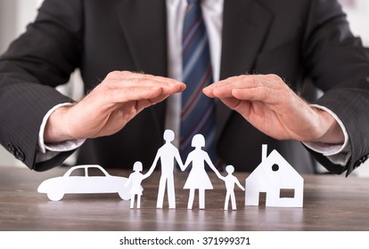 Concept of insurance with hands over a house, a car and a family - Shutterstock ID 371999371