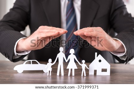Concept of insurance with hands over a house, a car and a family