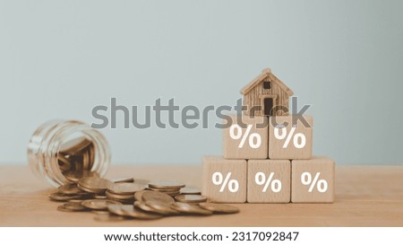 Concept of Interest rate financial mortgage rates, home loans, home refinance. Different size of percentage sign on stack of wooden cube blocks , miniature house on top and blurred coins and jar