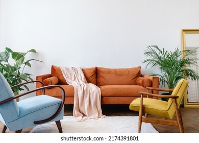 Concept interior design in the style of the 80s. Front view of elegant living room with vintage orange sofa, blue and yellow armchairs. Ergonomic couch in bright apartment with retro interior design - Shutterstock ID 2174391801