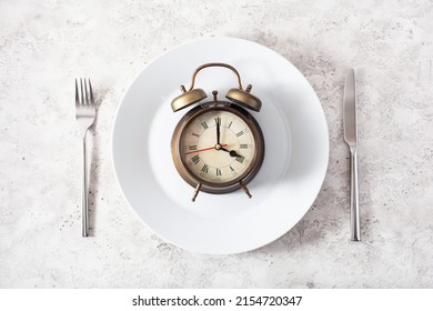 concept of intermittent fasting, ketogenic diet, weight loss. alarmclock on a plate