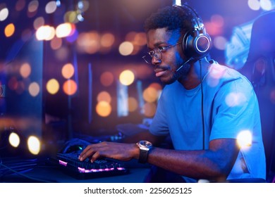 Concept internet web business security, trader man. Hacker American African with headphones working on computer with crypto stocks, neon color. - Shutterstock ID 2256025125