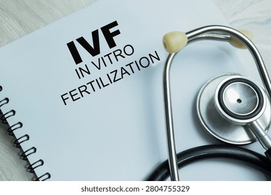 Concept of IVF - In Vitro Fertilization write on book isolated on Wooden Table. For embryo development and fertility treatment