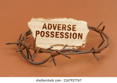 The concept of law and crime. On a brown surface, barbed wire and a cardboard sign with the inscription - Adverse Possession - Shutterstock ID 2167927767