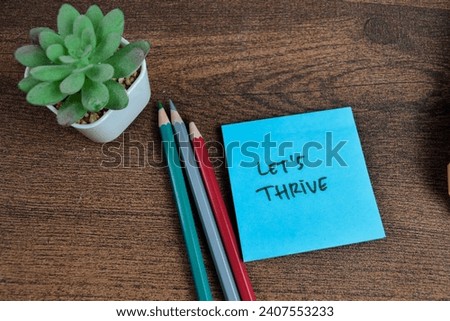 Concept of Let's Thrive write on sticky notes isolated on Wooden Table.