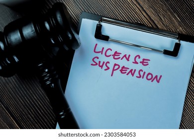 Concept of License Suspension write on paperwork with gavel isolated on Wooden Table.