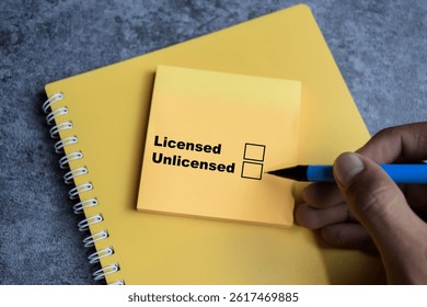 Concept of Licensed or Unlicensed write on sticky notes isolated on Wooden Table.