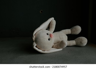 Concept: lost childhood, loneliness, pain and depression. Plush bunny lying down in a room