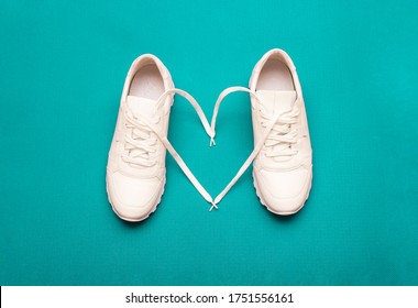 The concept of love for fitness. white sneakers with a heart, on a bright blue background. selective focus