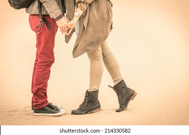 Concept of love relationship in autumn - Couple of young lovers kissing outdoors with closeup on legs and shoes - Desaturated nostalgic filtered look