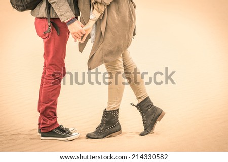 Concept of love relationship in autumn - Couple of young lovers kissing outdoors with closeup on legs and shoes - Desaturated nostalgic filtered look
