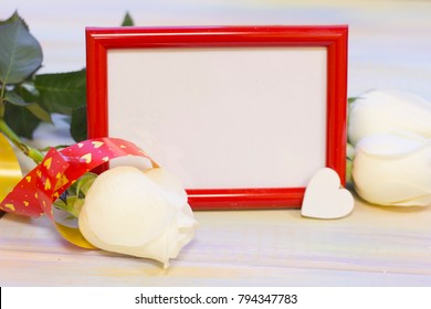 The Concept Of Love, Wedding, Proposal, Anniversary, St. Valentine's Day, Mother's Day With A Red Photo Frame, Whte Roses And Decorations On A Light Wooden Table