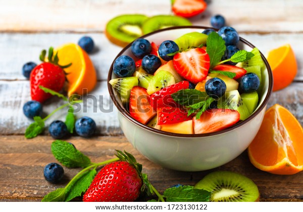 Concept of low calories delicious desserts.\
Summer fresh bowl with colorful fruit salad. Healthy natural\
organic food. Tasty sweet snack, light simple tasty lunch. Close up\
macro view wooden\
backgroun